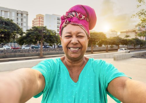 Man smiling at camera in bright blue top and pink turban