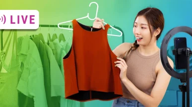 A Chinese woman showing the camera a shirt for sale on a shopping live stream.