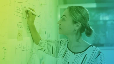 A woman illustrating a content strategy on a whiteboard in an office