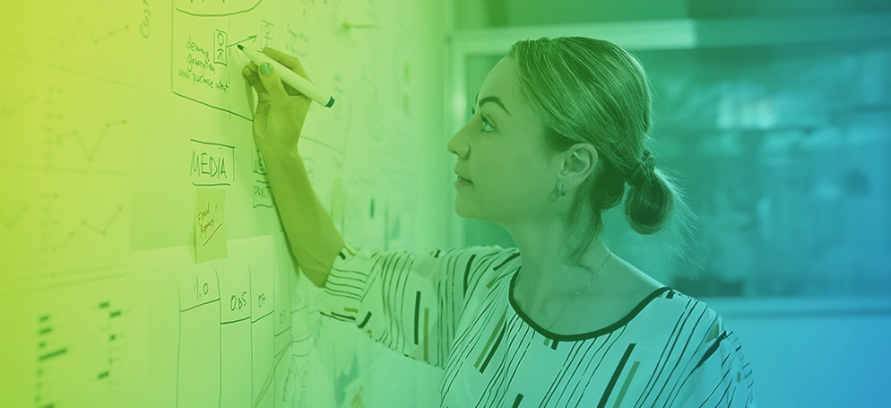 A woman illustrating a content strategy on a whiteboard in an office