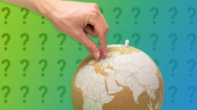 A hand placing a pin into a globe