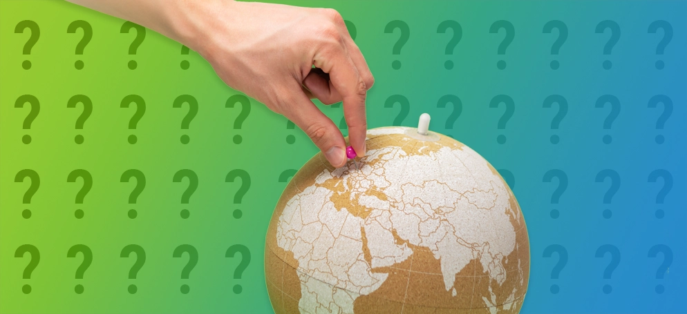A hand placing a pin into a globe