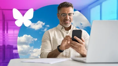 man in an office using a phone and laptop