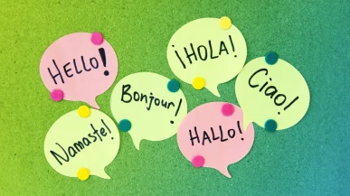 Speech bubble post it notes on a cork board with greetings written in different languages