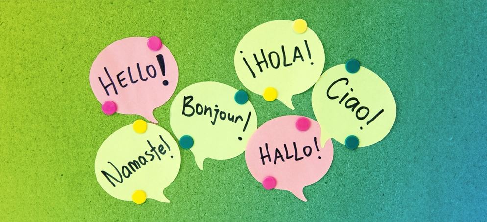 Speech bubble post it notes on a cork board with greetings written in different languages