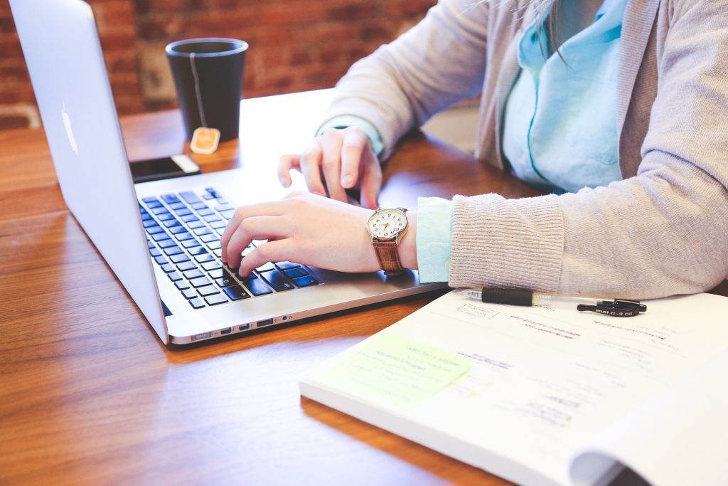 person at desk with laptop and drink