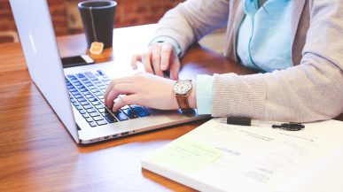 person at desk with laptop and drink
