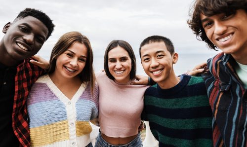 Portrait of multiracial friends having fun smiling on camera outdoor - Focus on center girl face